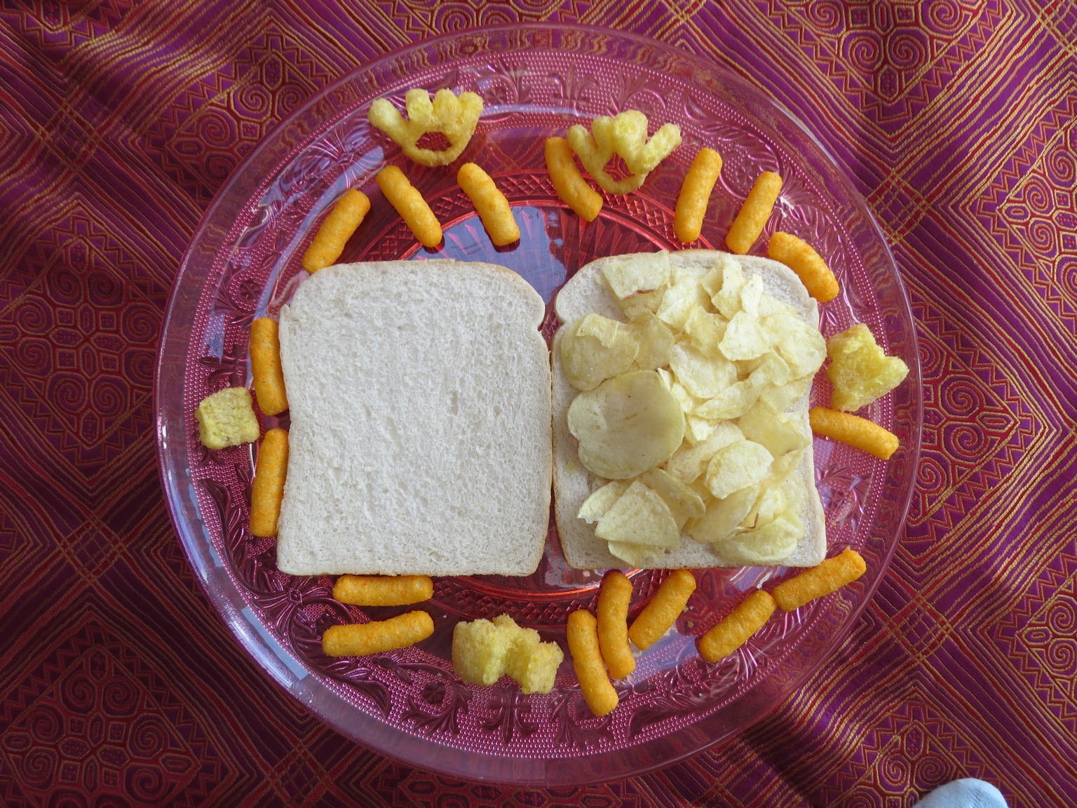 Overhead view of potato crisps on white bread with snacks