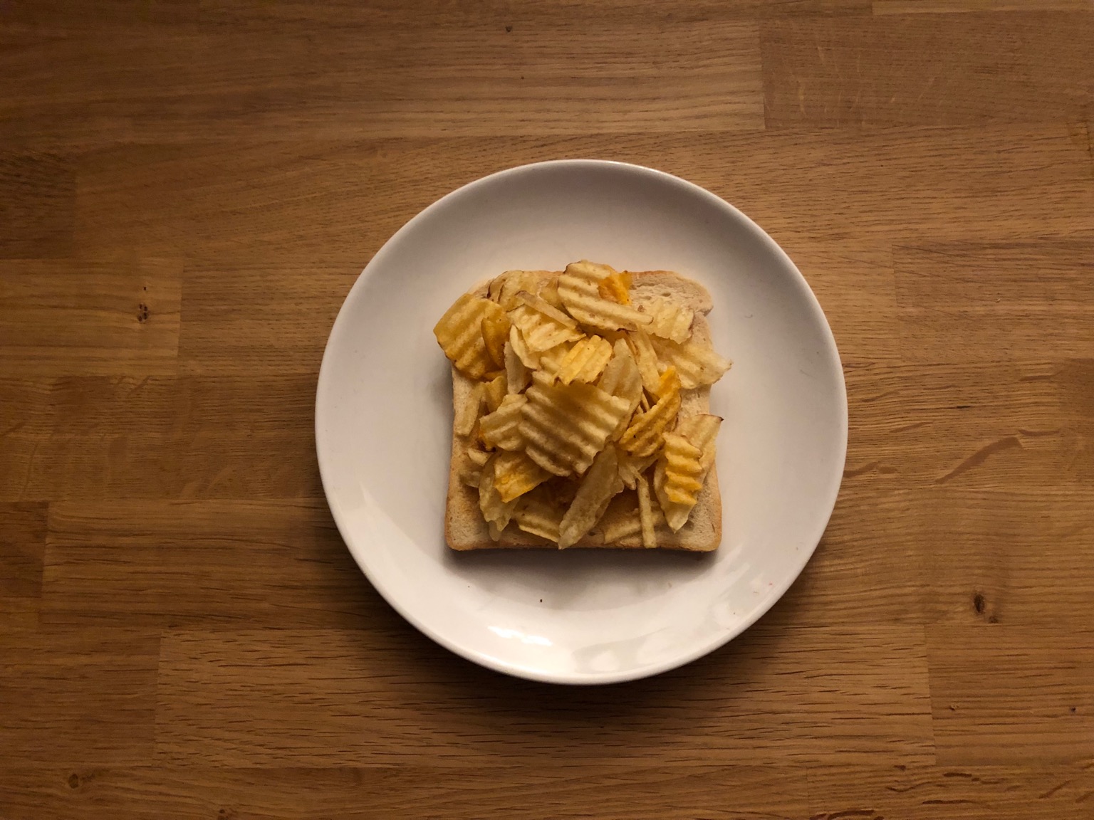 Overhead view of crinkle-cut crisps on sliced bread
