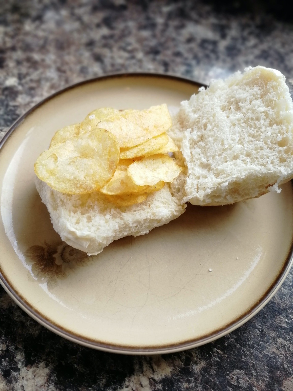 Open white roll with potato crisps placed on it