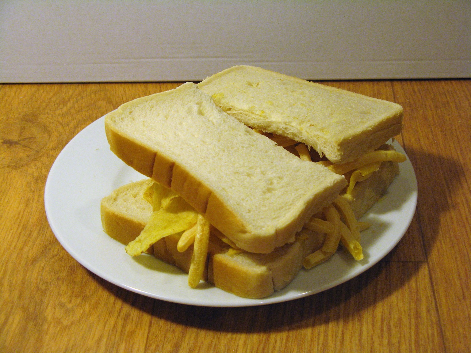 Halved sandwich containing crisps and French Fries
