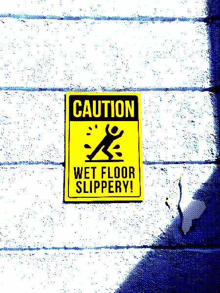 Yellow caution sign saying "WET FLOOR SLIPPERY!" with a representation of tripping on water above.