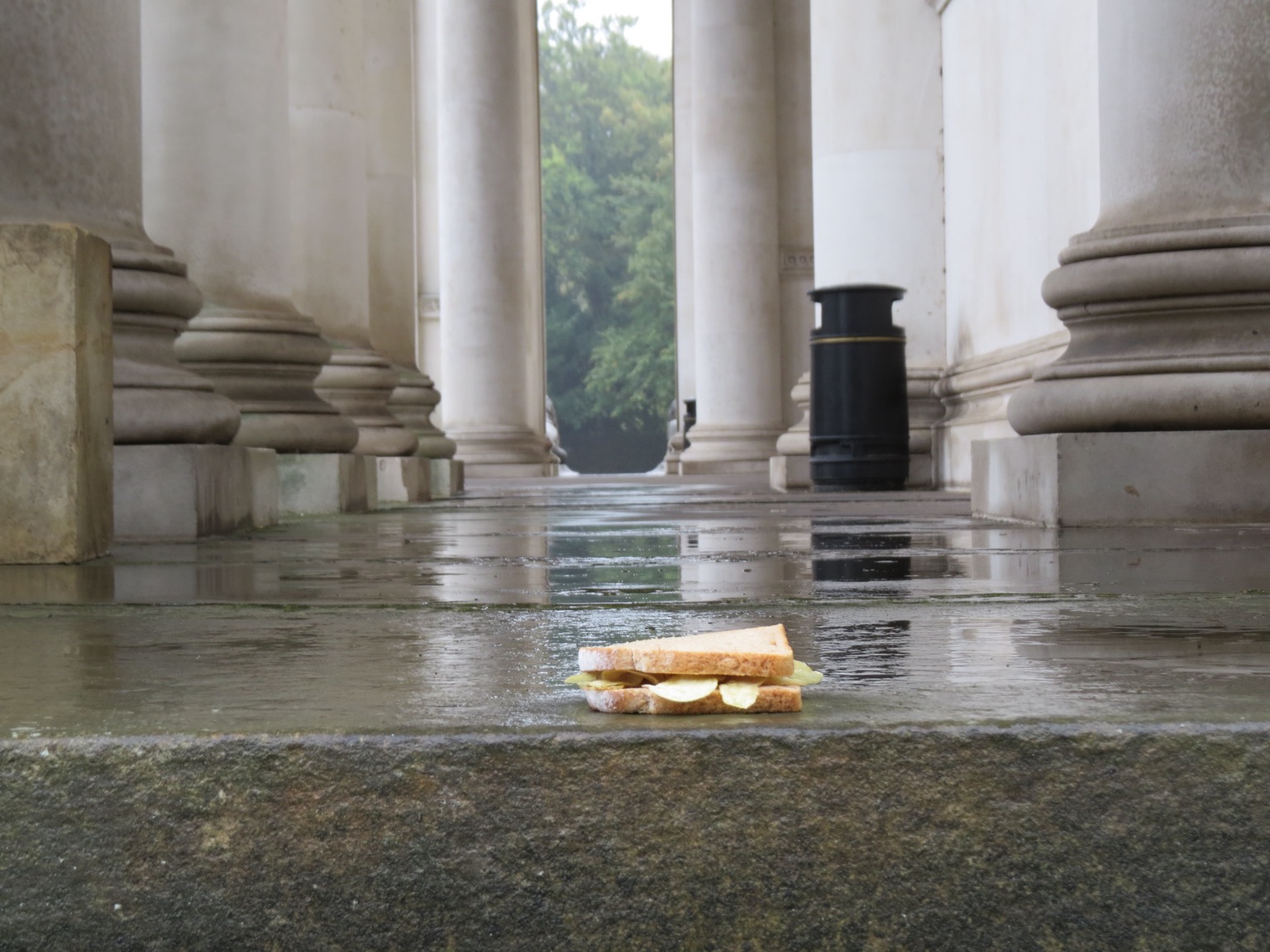 Crisp sandwich in front of stone columns and a bin