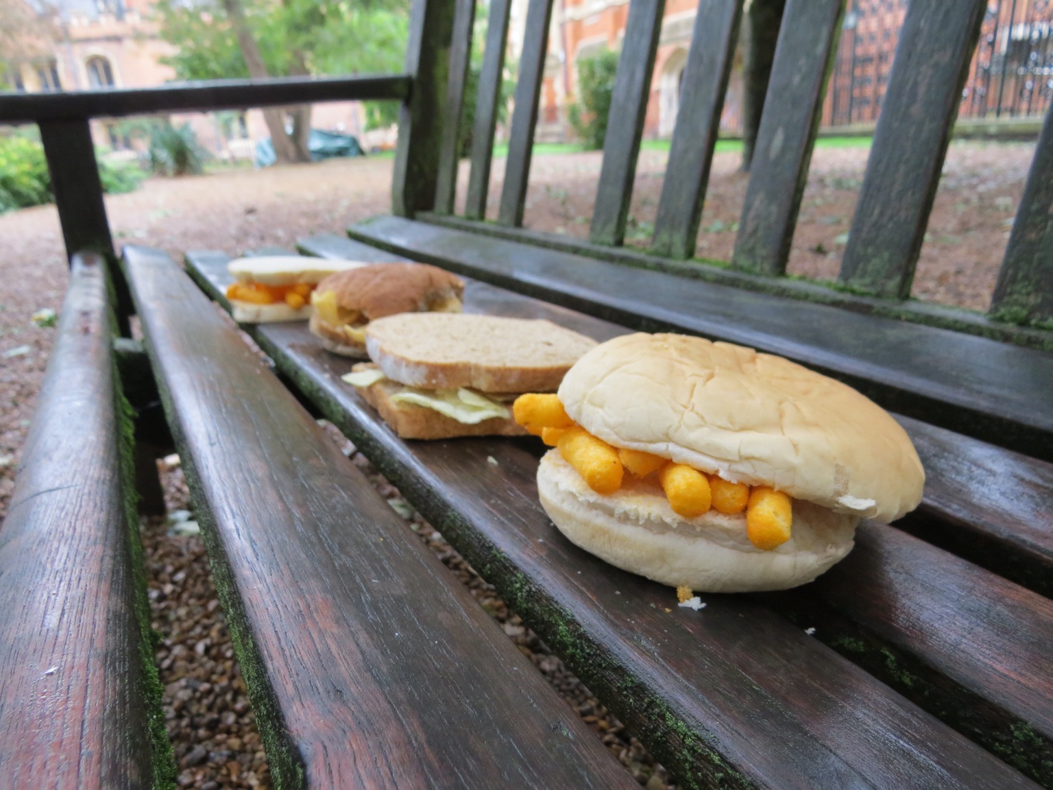 Four sandwiches on a park bench, Wotsits roll at front