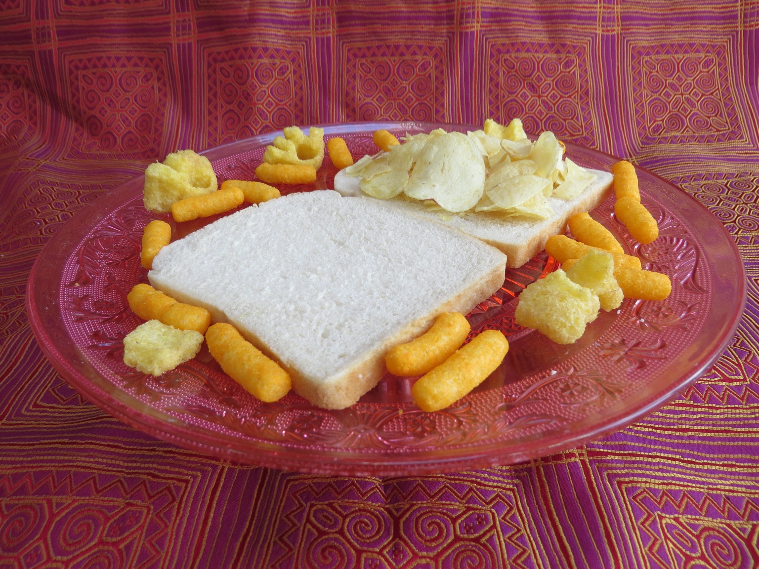 Open potato crisp sandwich surrounded by corn snacks