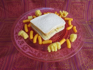 Potato crisp sandwich on plate surrounded by corn snacks