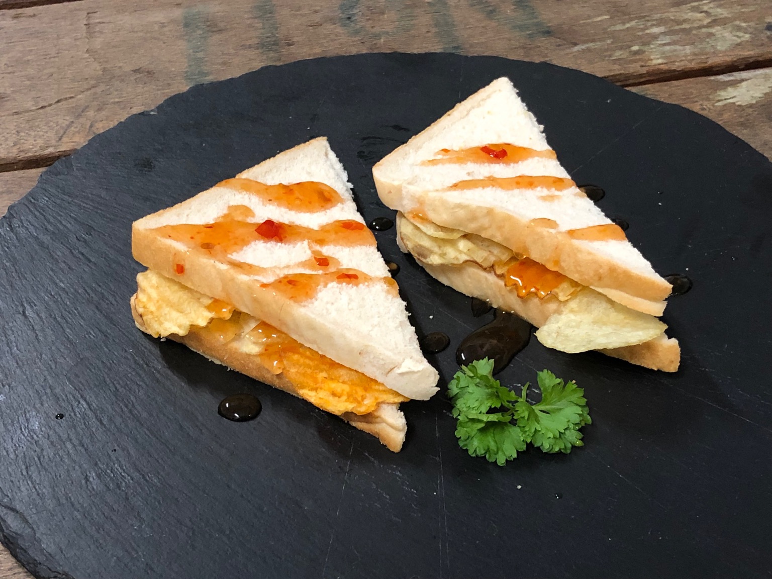 Crisps in white bread with drizzle and garnish