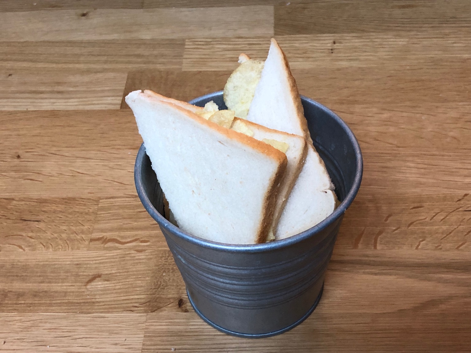 Crisps in sliced white bread in a metal bucket