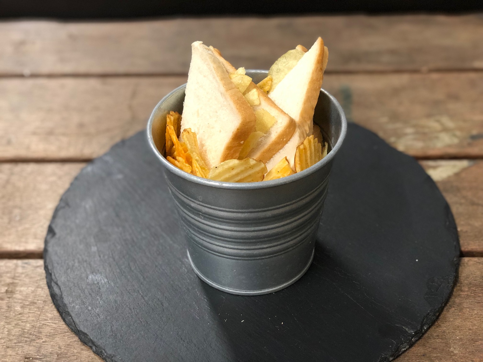 Metal bucket containing crisps and sandwich