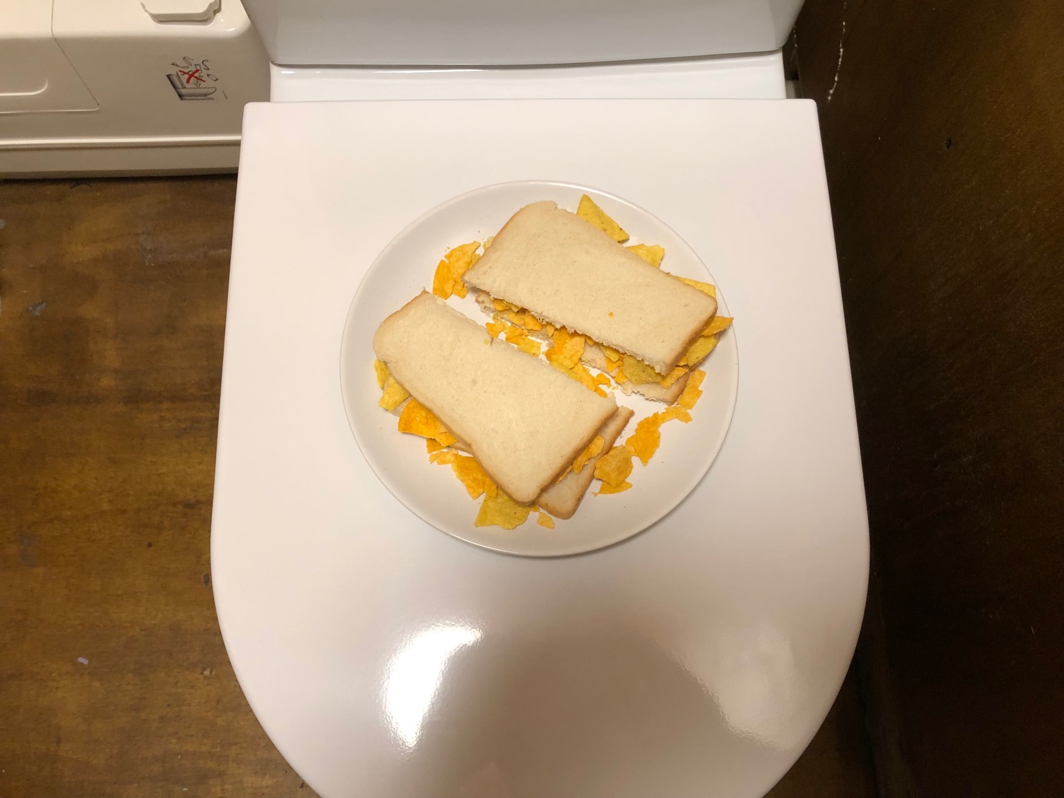 Doritos in white sliced bread placed on a toilet seat