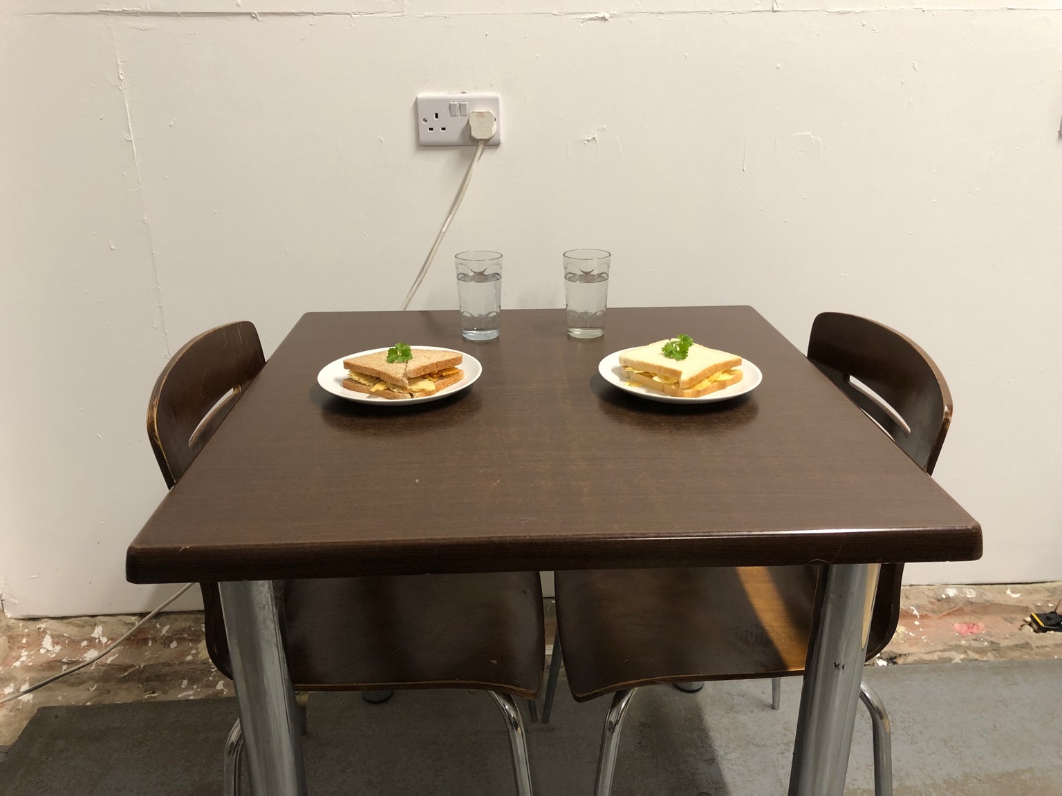 Dining table with two crisp sandwiches laid out