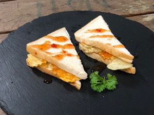 Crisps in white bread with drizzle and garnish