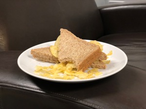 Potato crisps in sliced brown bread with bite taken