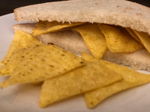 Doritos in and alongside diagonally-cut sandwich