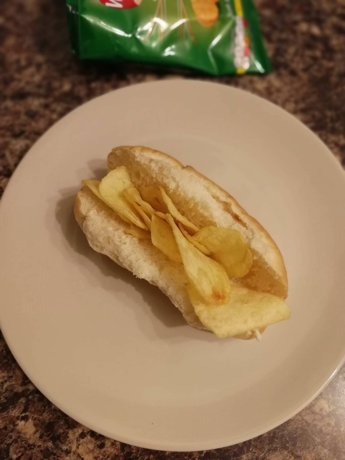 Finger roll filled with potato crisps, crisp bag visible