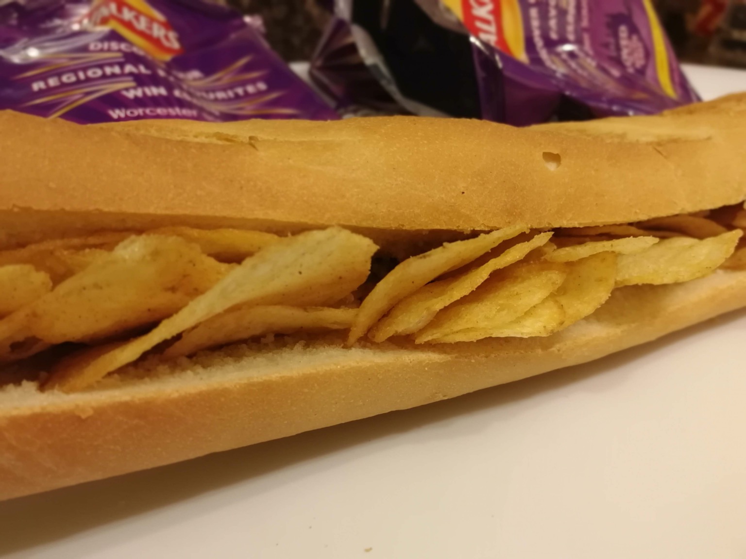 Close up of crisp-filled baguette with empty bags