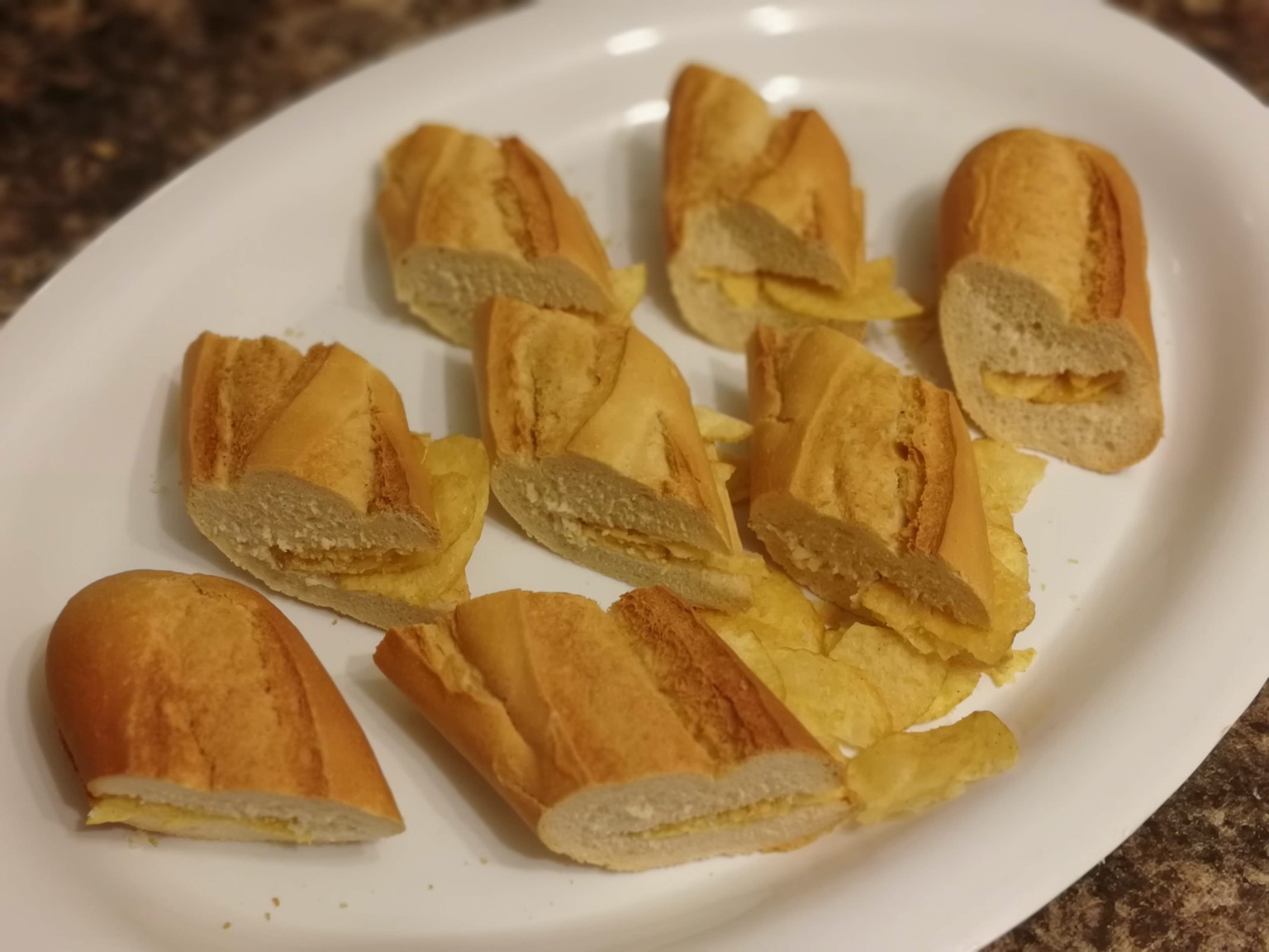 Eight baguette segments filled with potato crisps