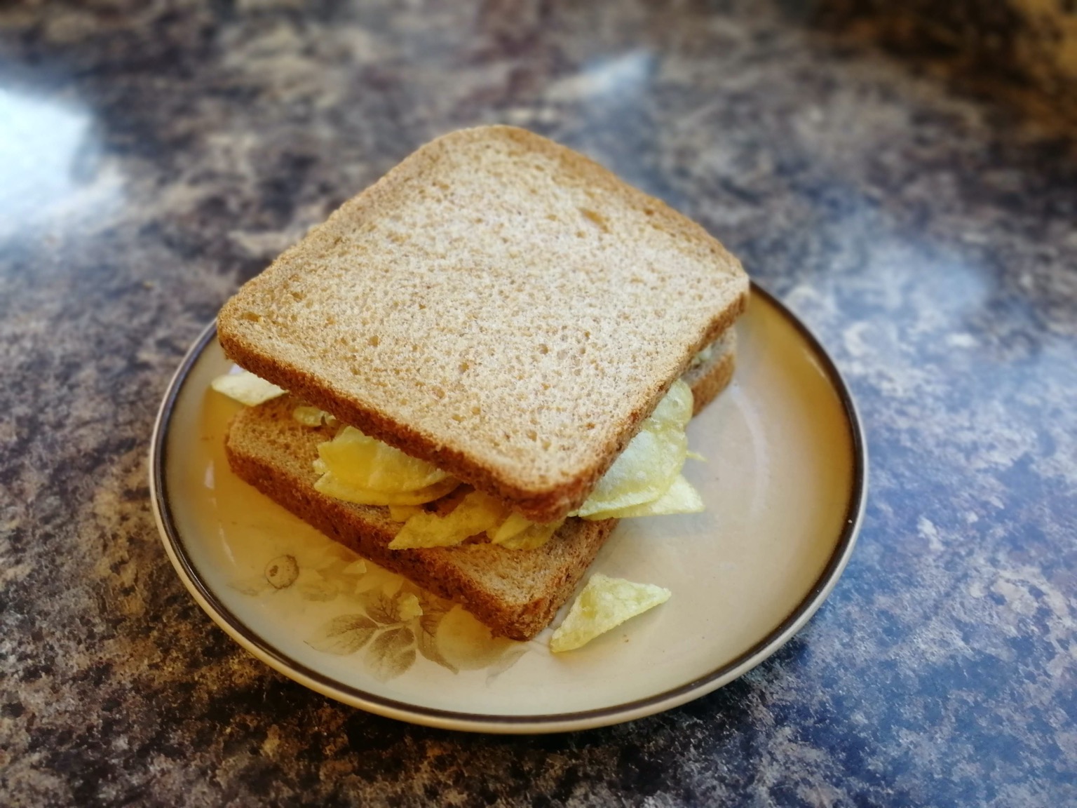 Brown crisp sandwich on a plate on a granite surface