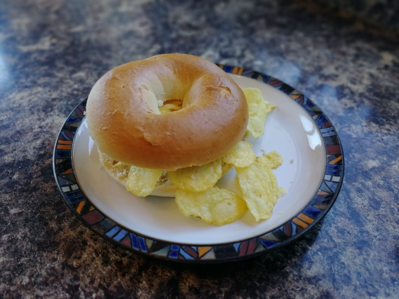 Bagel overfilled with potato crisps on a plate