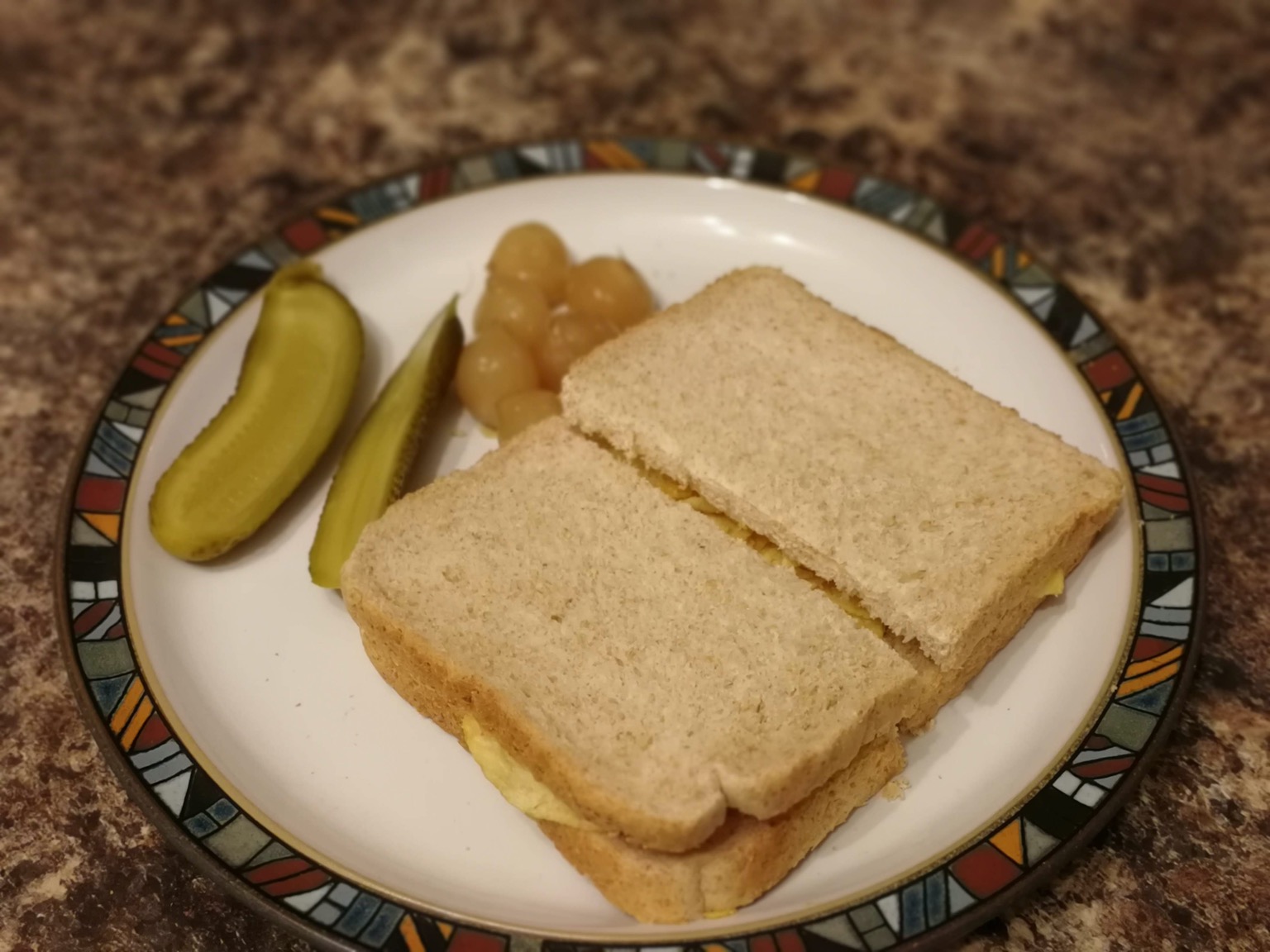 Halved brown crisp sandwich alongside pickles