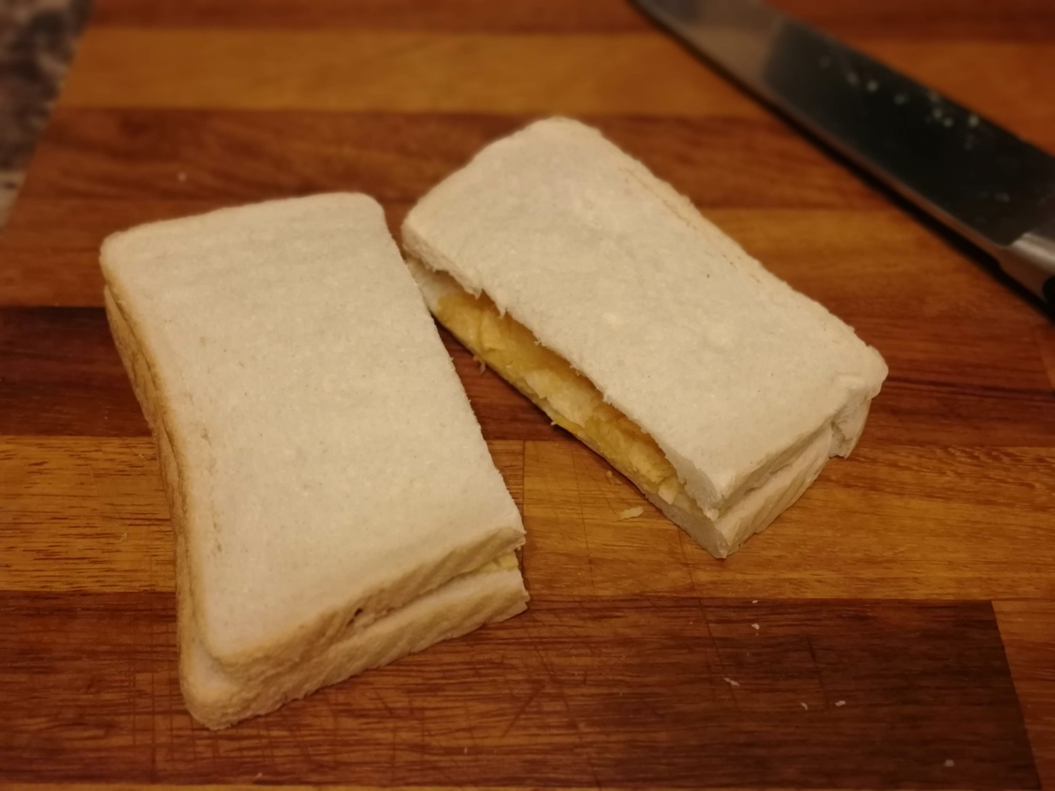 Halved white crisp sandwich alongside kitchen knife