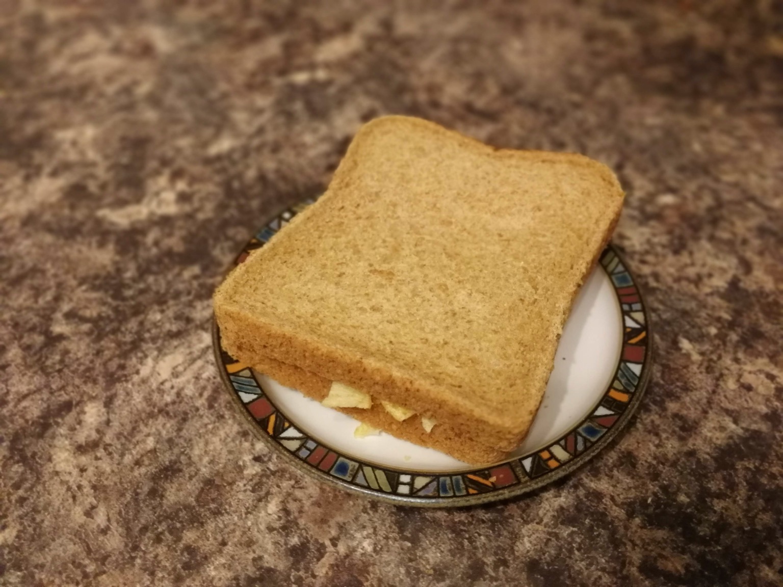 Brown crisp sandwich on a plate on granite
