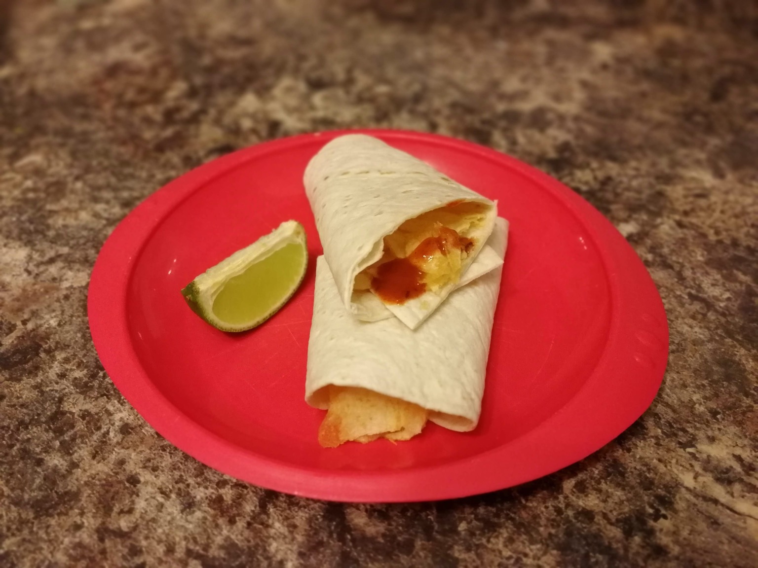 Wrap containing crisps and sauce alongside lime