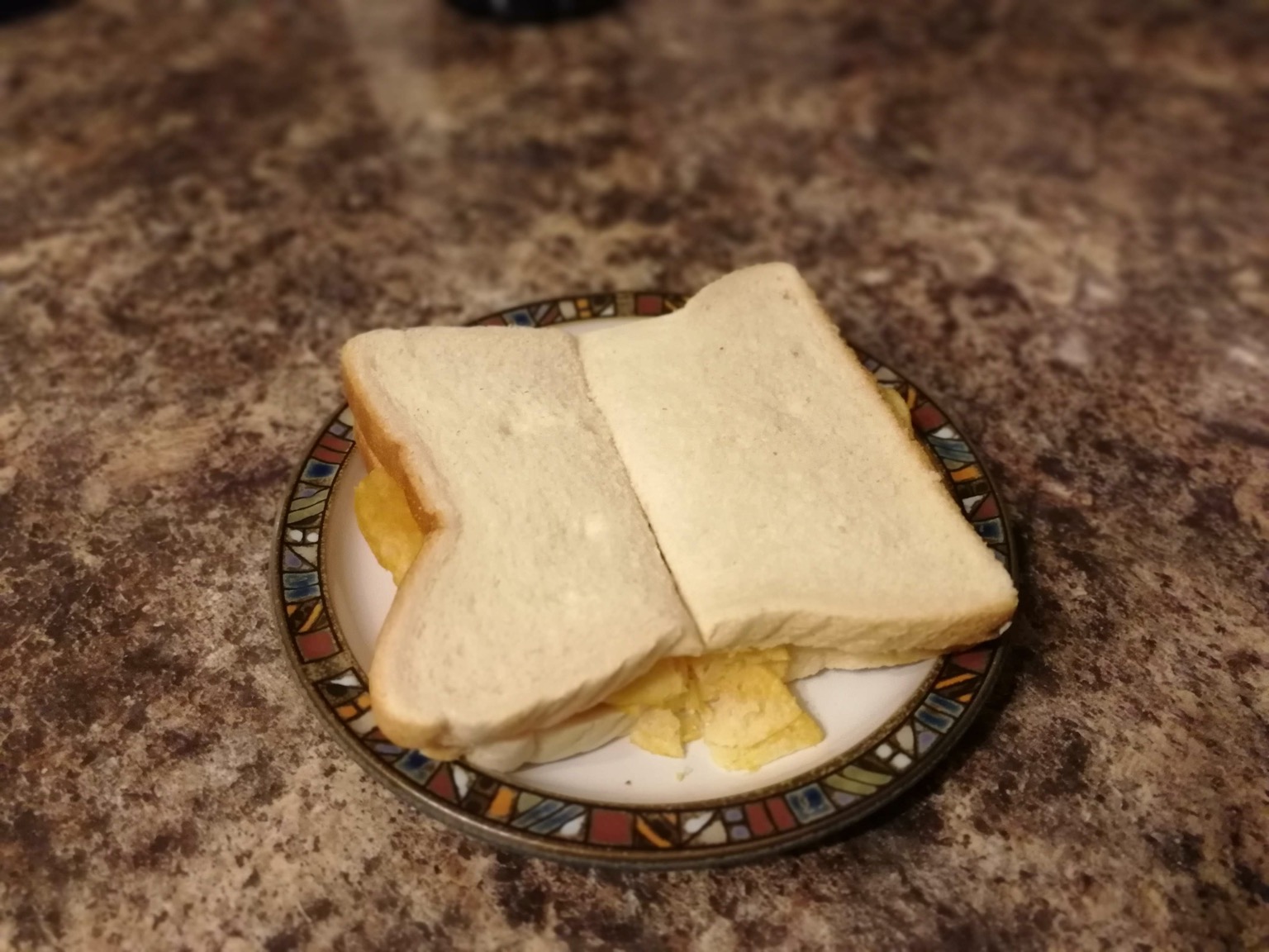 Halved white crisp sandwich on a plate on granite