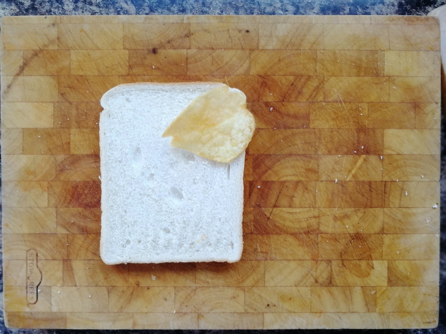 One crisp on white bread on a chopping board