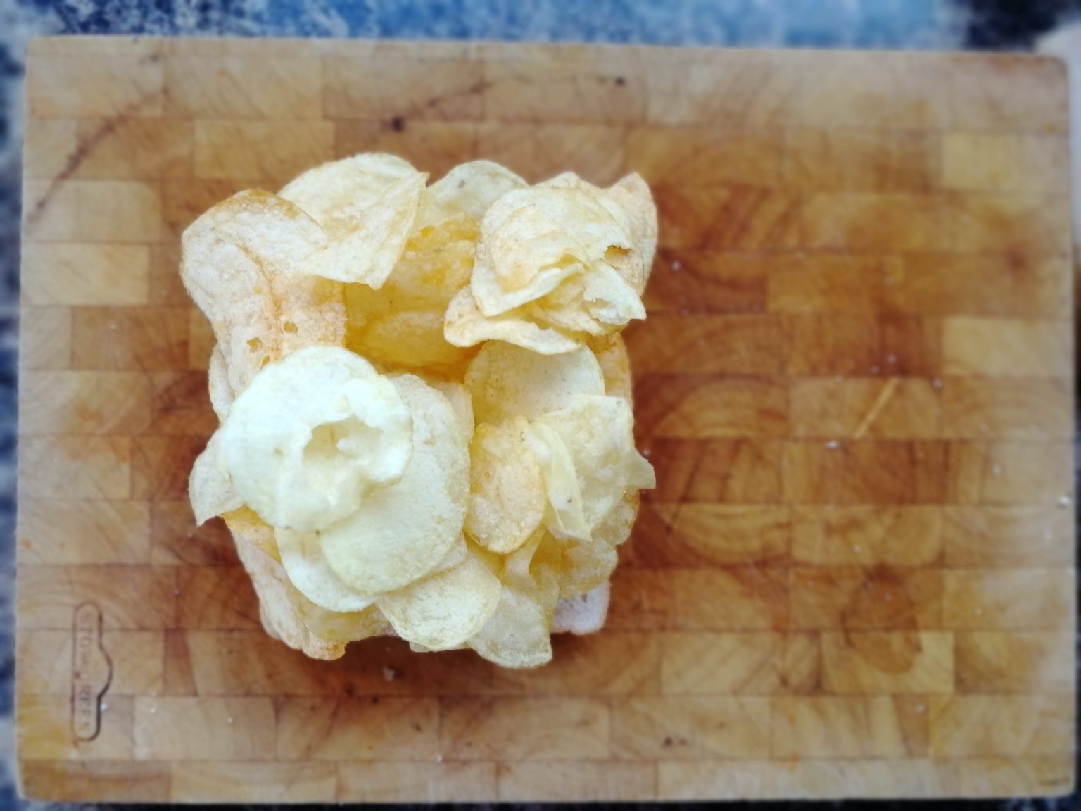 Many crisps on white bread on a chopping board