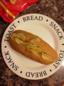 Split finger roll filled with crisps, bag alongside