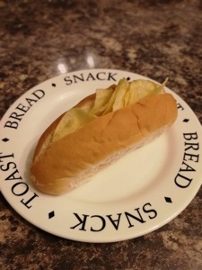 Split finger roll filled with potato crisps on a plate