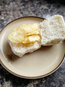 Open white roll with potato crisps placed on it