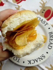 Hand holding white roll containing crisps, festive setting