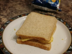 Brown crisp sandwich on a plate alongside bag