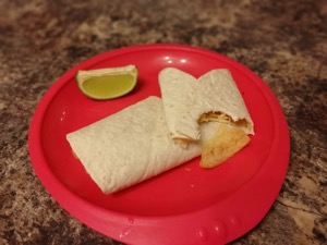 Crisp-filled wrap with a bite taken out alongside lime