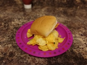 White roll overflowing with crisps on a pink plastic plate