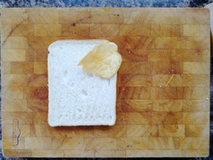 One crisp on white bread on a chopping board