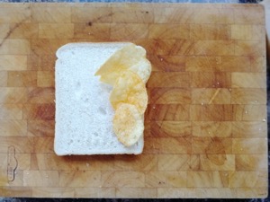 Three crisps on white bread on a chopping board