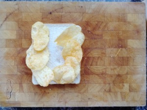 Seven crisps on white bread on a chopping board