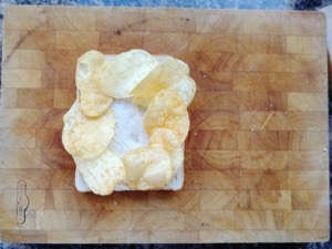 Eight crisps on white bread on a chopping board