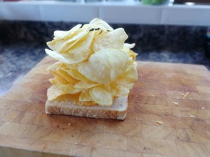 Lots of crisps piled onto white bread