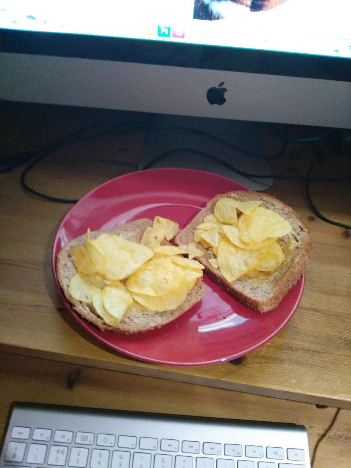 Potato crisps on brown bread in front of an iMac