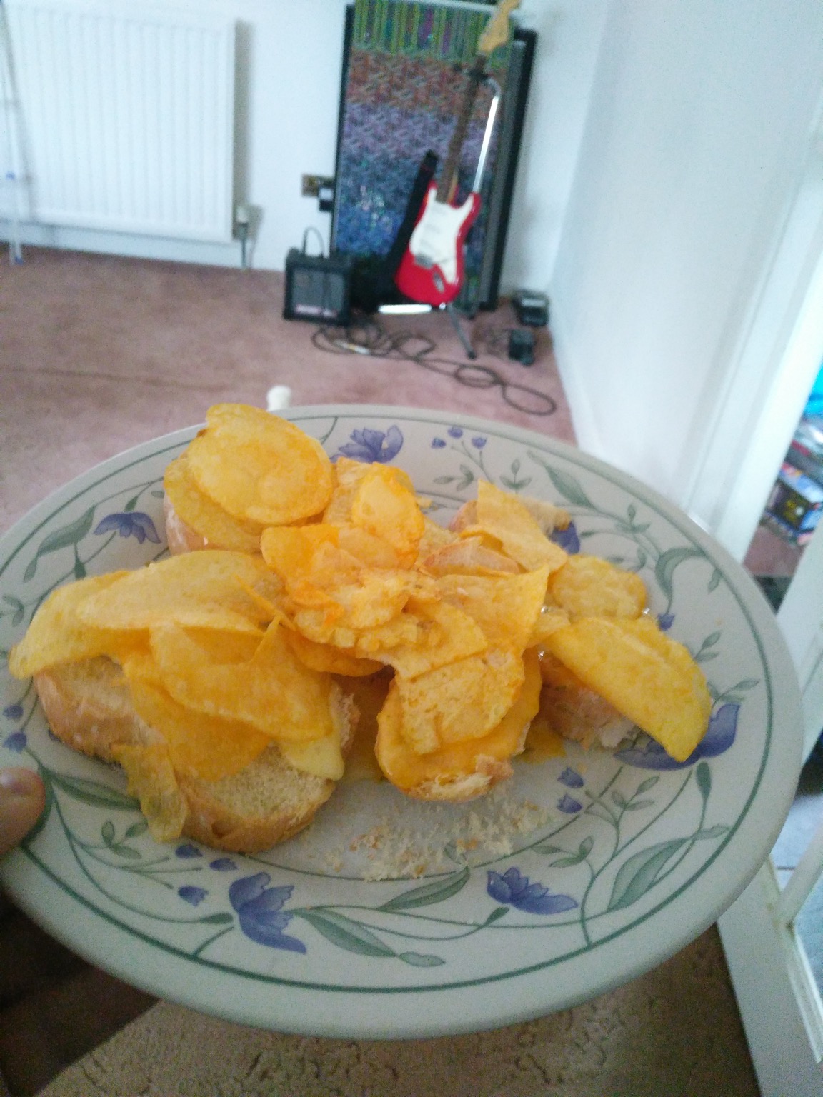 Crisps on white bread approaching a guitar