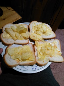 Four slices of white bread with crisps and cheese