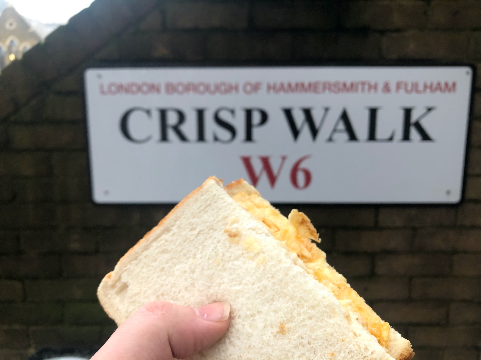 Half of a crisp sandwich held up to Crisp Walk sign