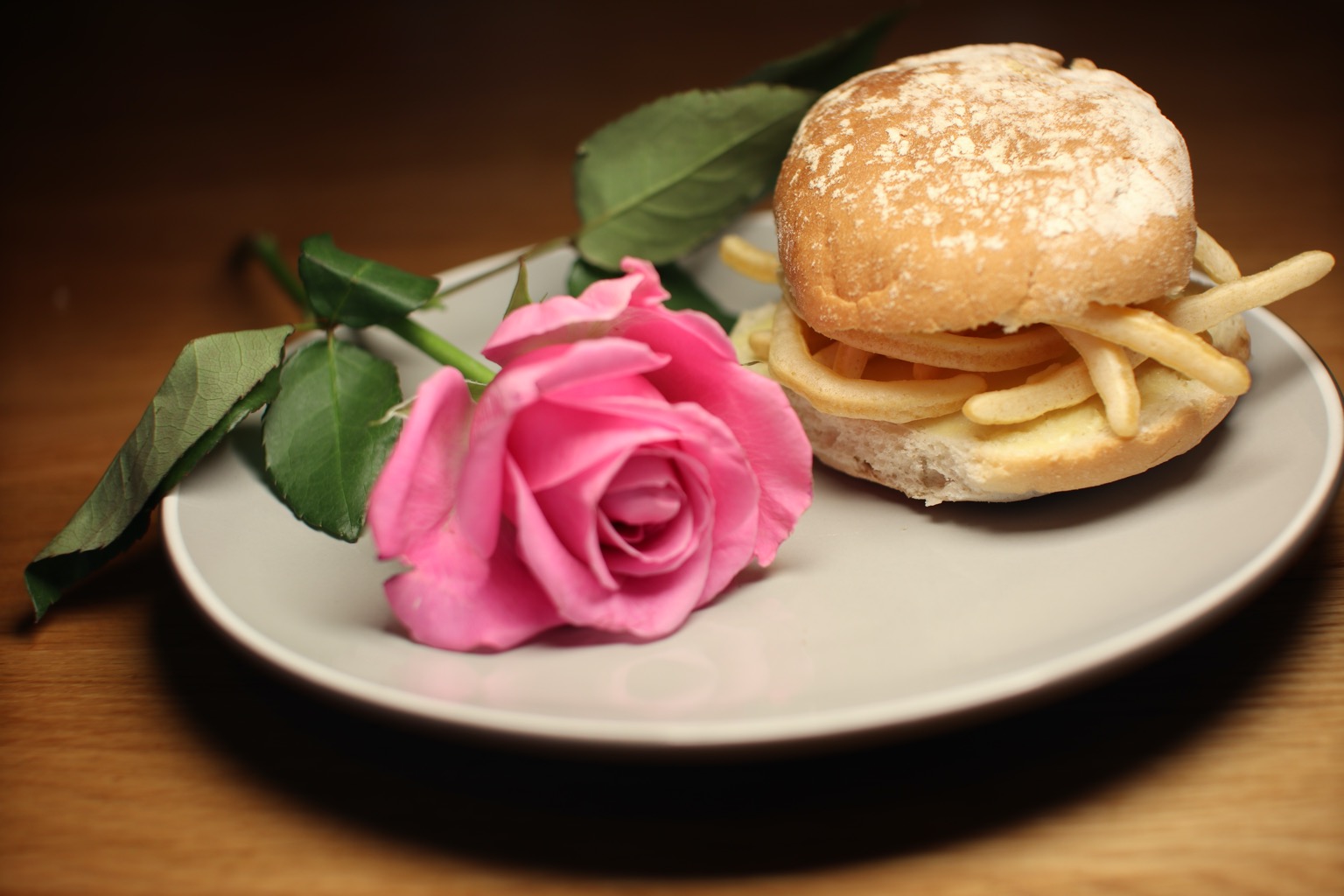 Roll containing French Fries alongside a pink rose