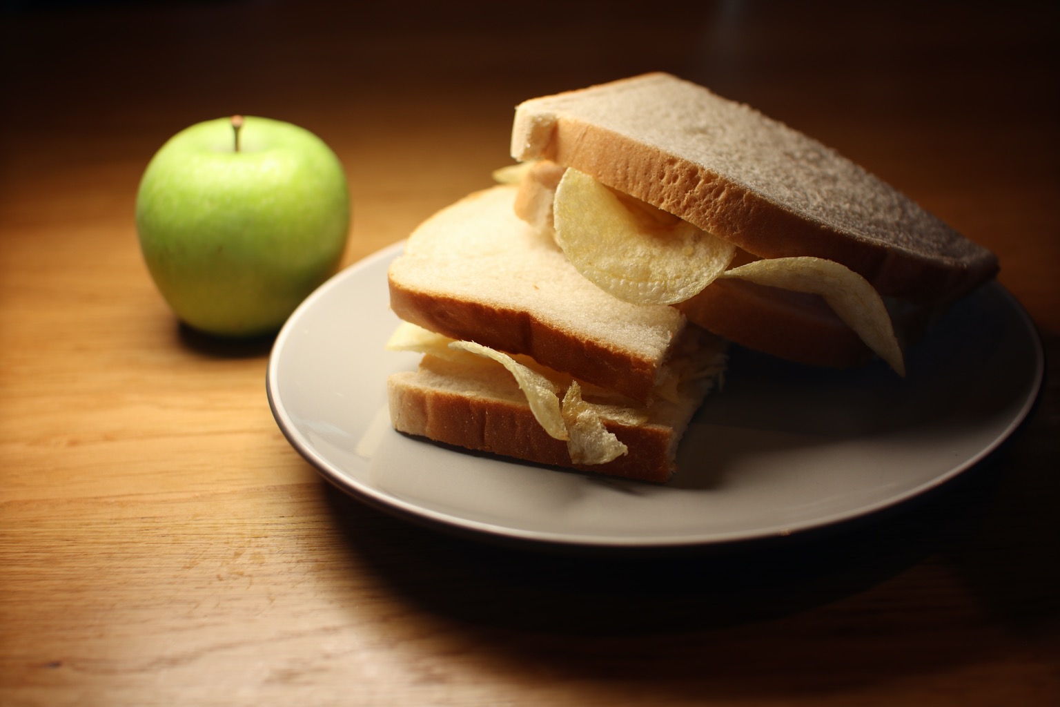 White crisp sandwich cut in half alongside an apple
