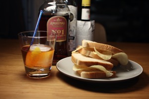 Halved white crisp sandwich alongside rum cocktail