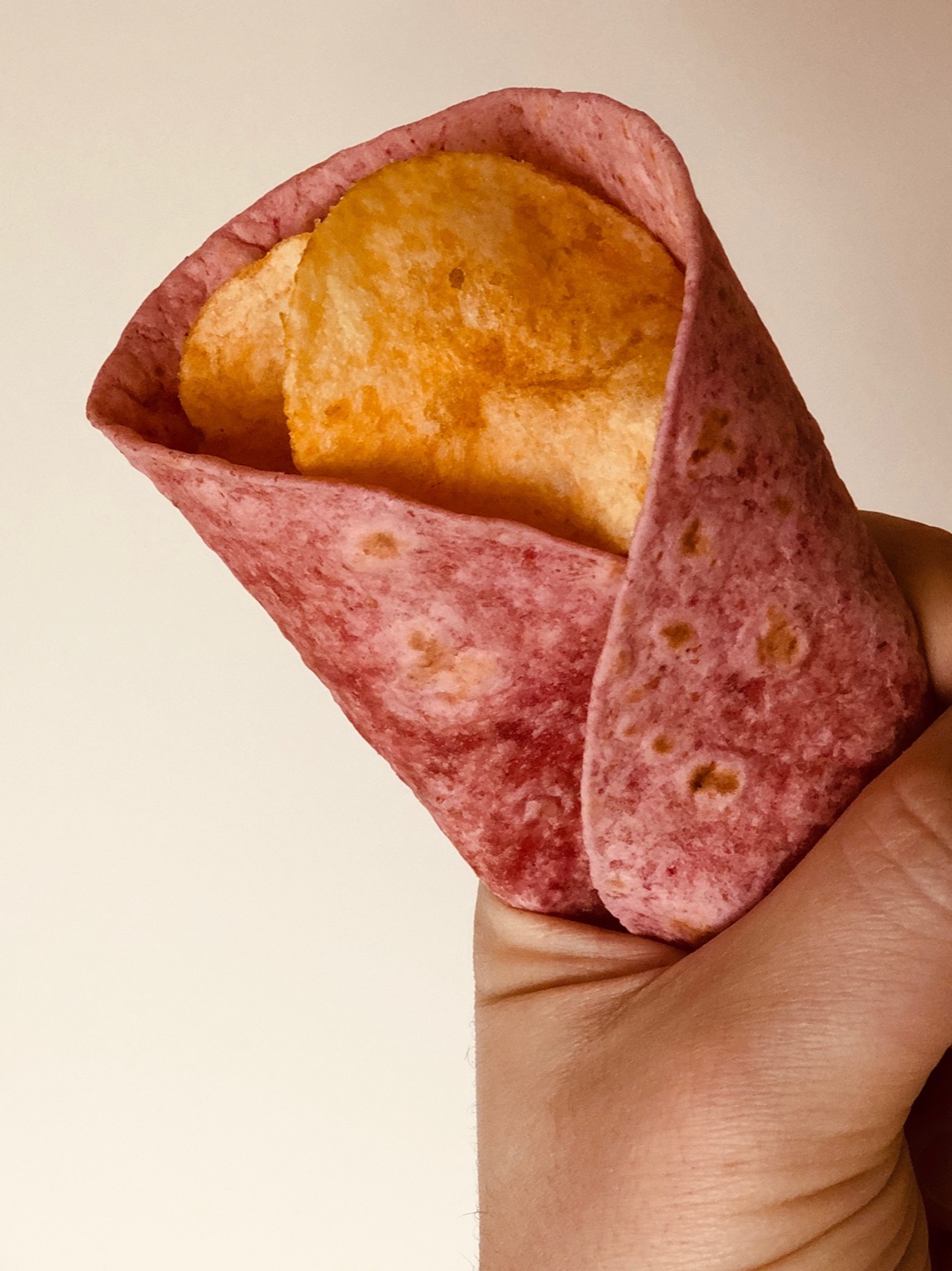 Close-up of crisps held in a pink tortilla wrap