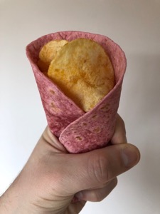 Potato crisps held in a pink tortilla wrap